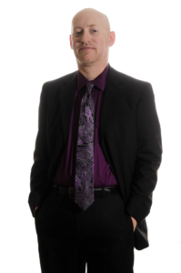 A photo of Michael Hanscom, a bald caucasian male with light facial hair wearing a dark suit