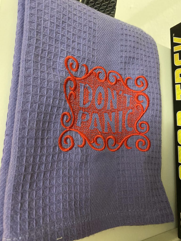 Photo of a hand towel embroidered with the words 'Don't Panic' in large, friendly letters