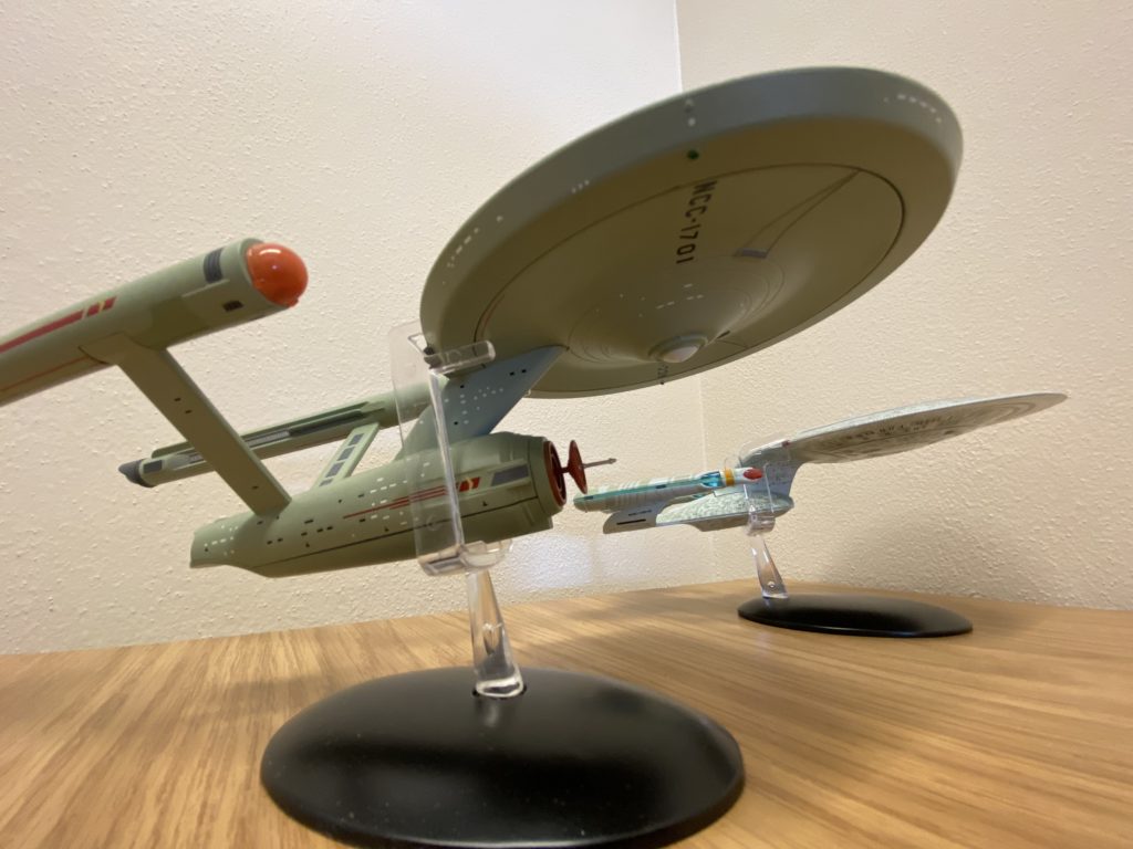 Two models of the USS Enterprise, one the original TOS version, one the Next Generation version, on a desktop.