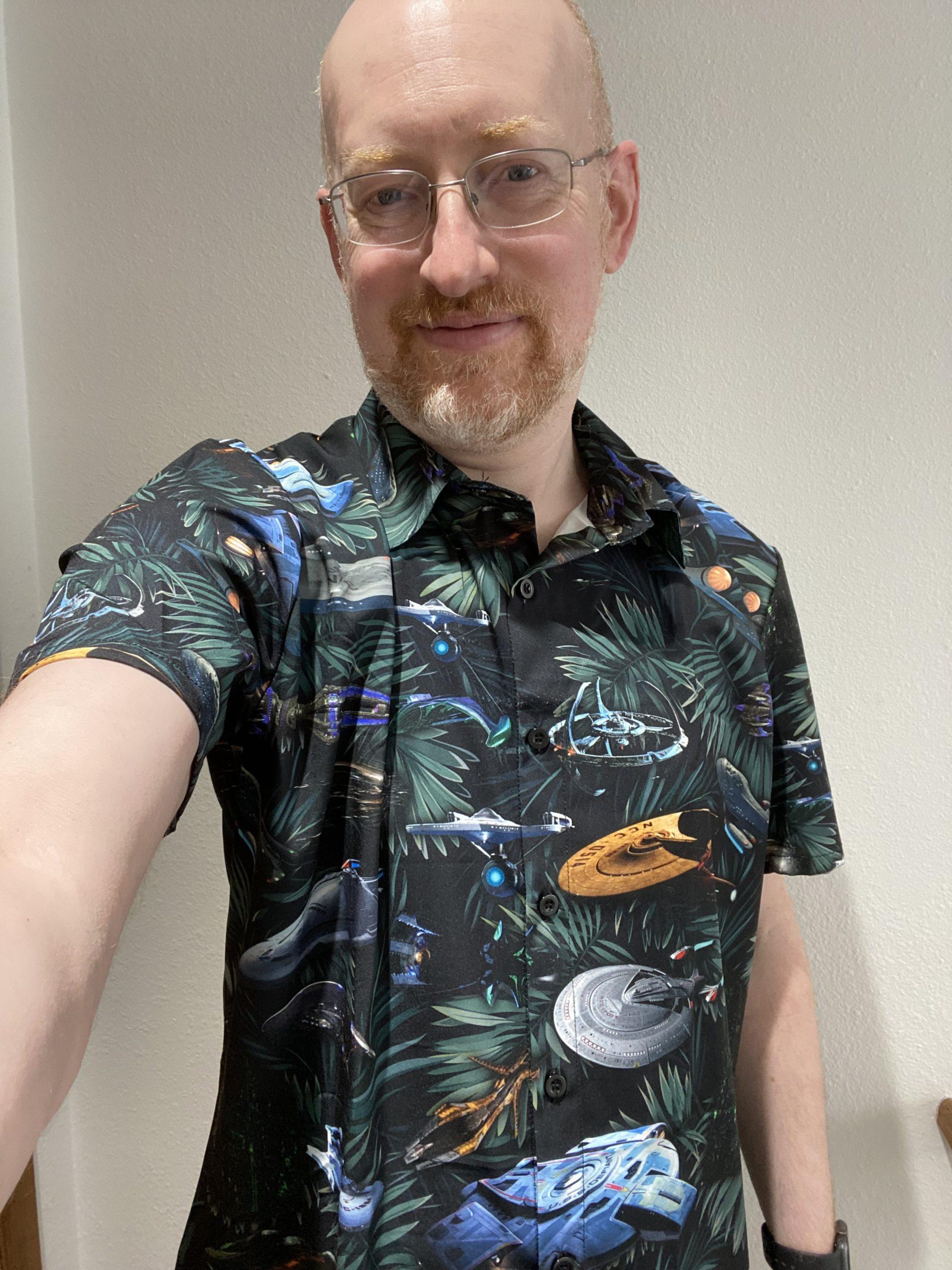 Me wearing a black short-sleeve button-up shirt with a Hawaiian shirt style print of tropical leaves and various Star Trek ships.