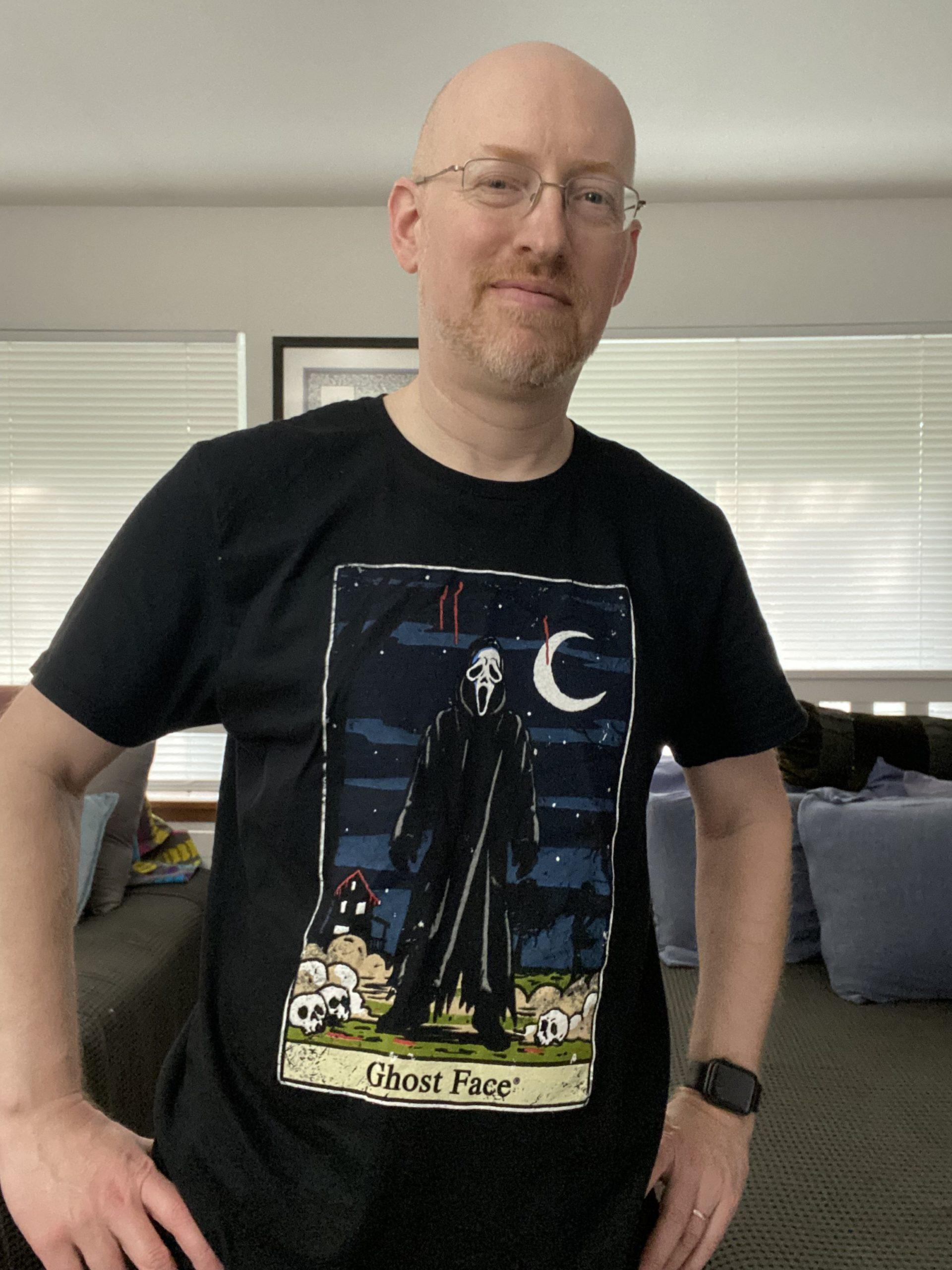 Me wearing a black t-shirt with an image of the Ghost Face killer from the Scream film series drawn in the style of a Rider-Waite tarot card.