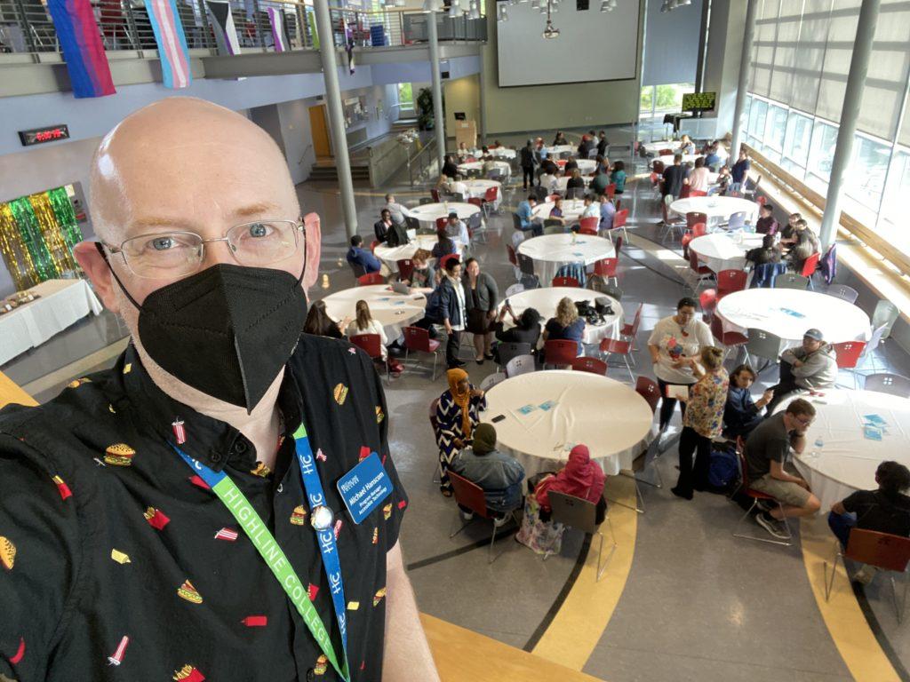 Me on an upper level of the school’s student union building; below me are a number of round tables with students and family members sitting and talking.