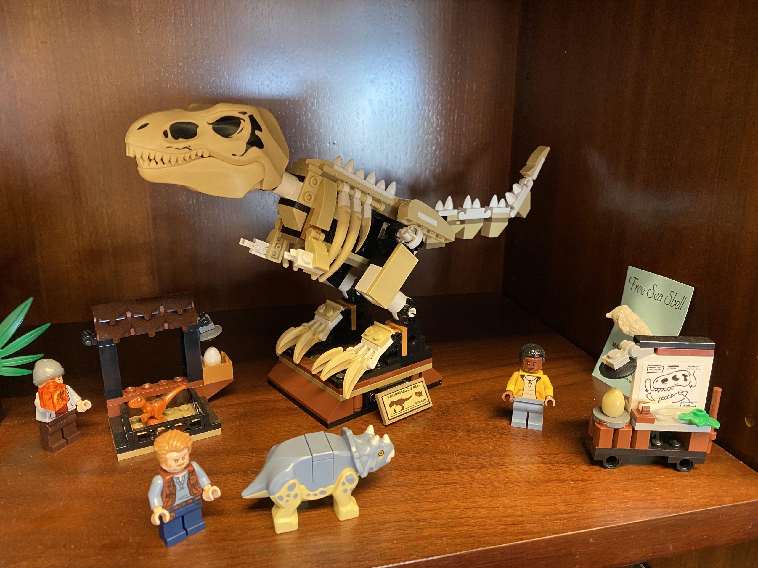 A Lego set from Jurassic World that includes a T-Rex skeleton, an educational display, and a baby triceratops.
