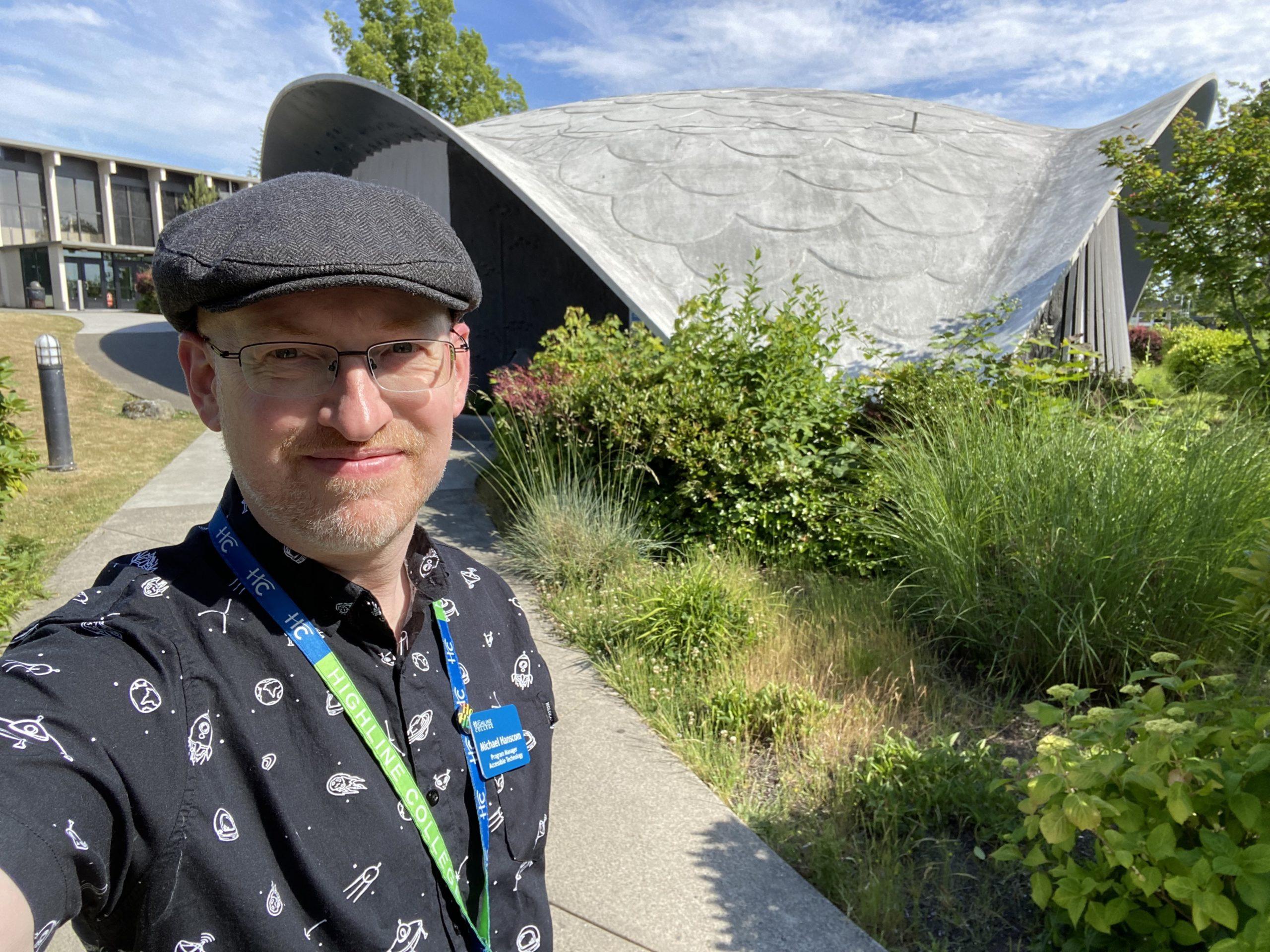 Me standing outside in front of an old building with a curved and sloped roof that looks vaguely like a turtle's shell.