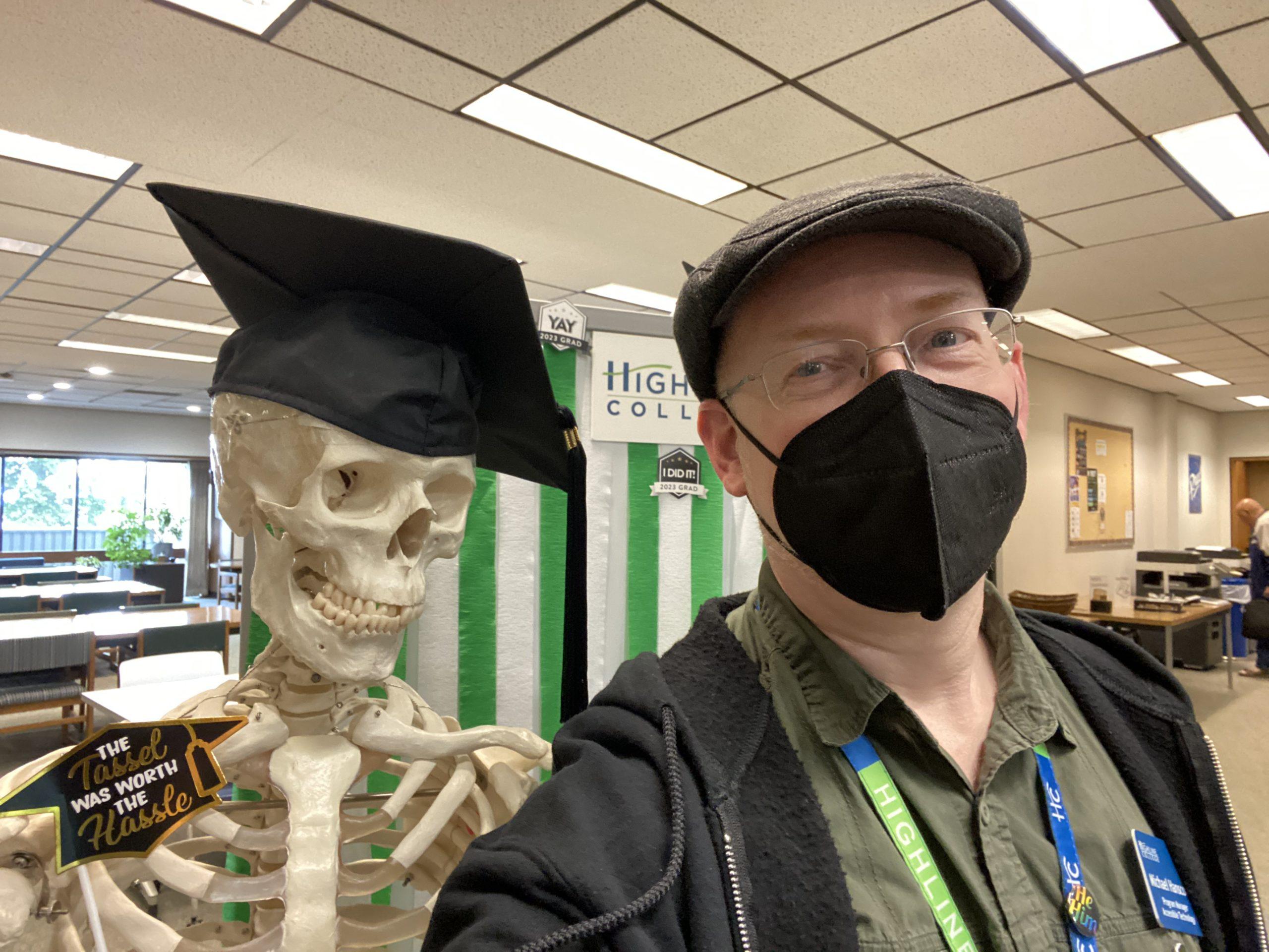 Me in the college library, standing next to a skeleton wearing a graduation cap.