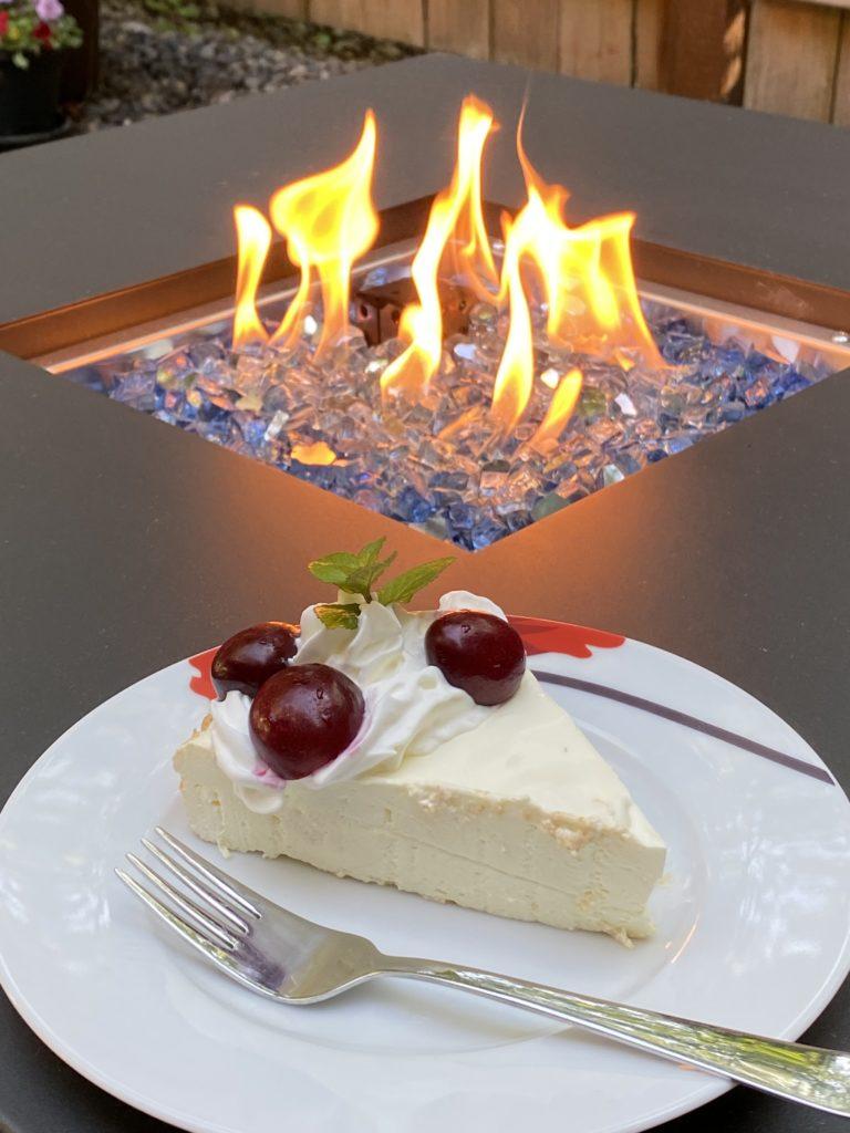 The fire pit table; a small plate with a pretty piece of cheesecake is in the foreground.
