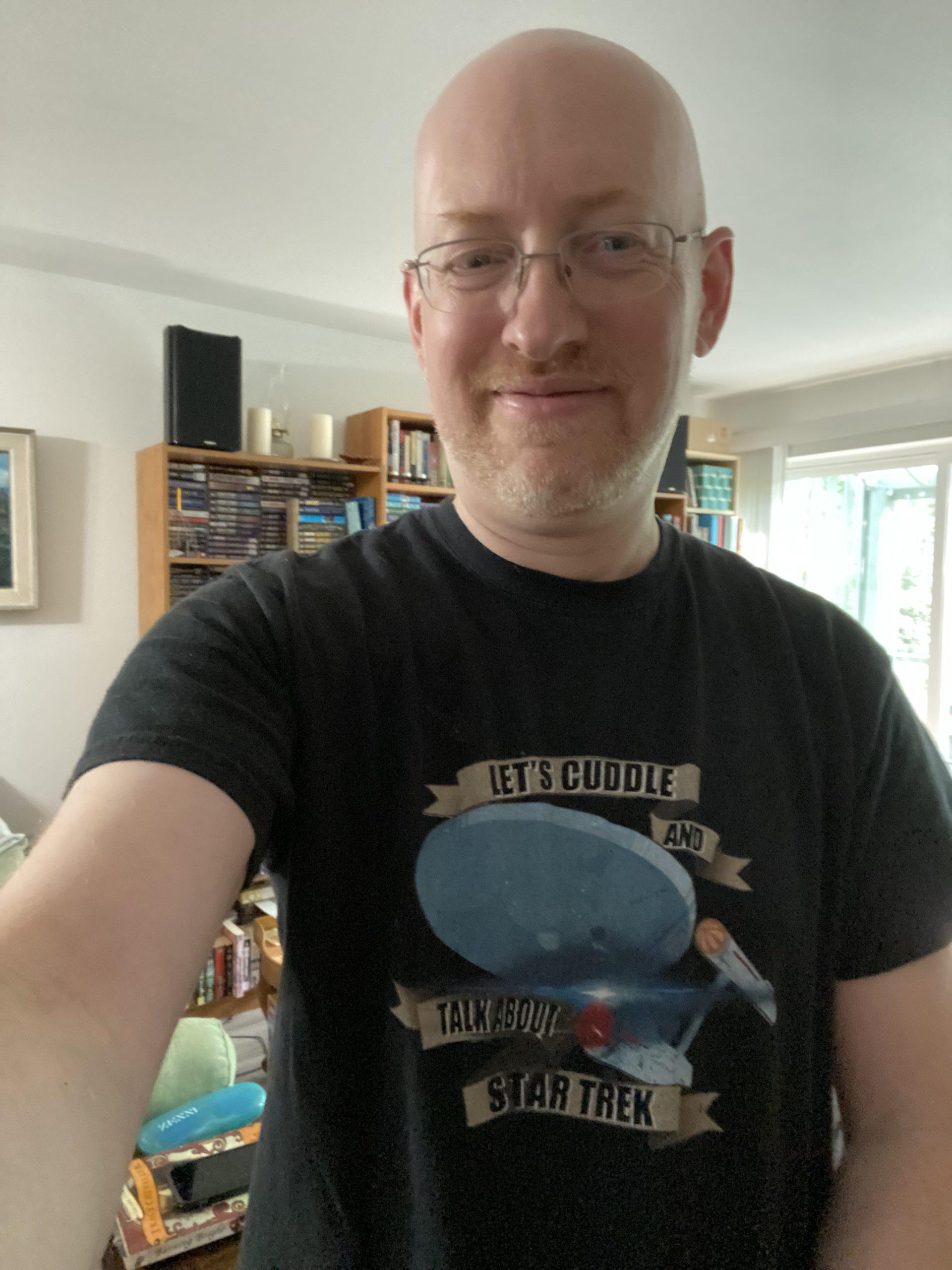 Me wearing a t-shirt with an illustration of the original USS Enterprise and text saying "Let's cuddle and talk about Star Trek".