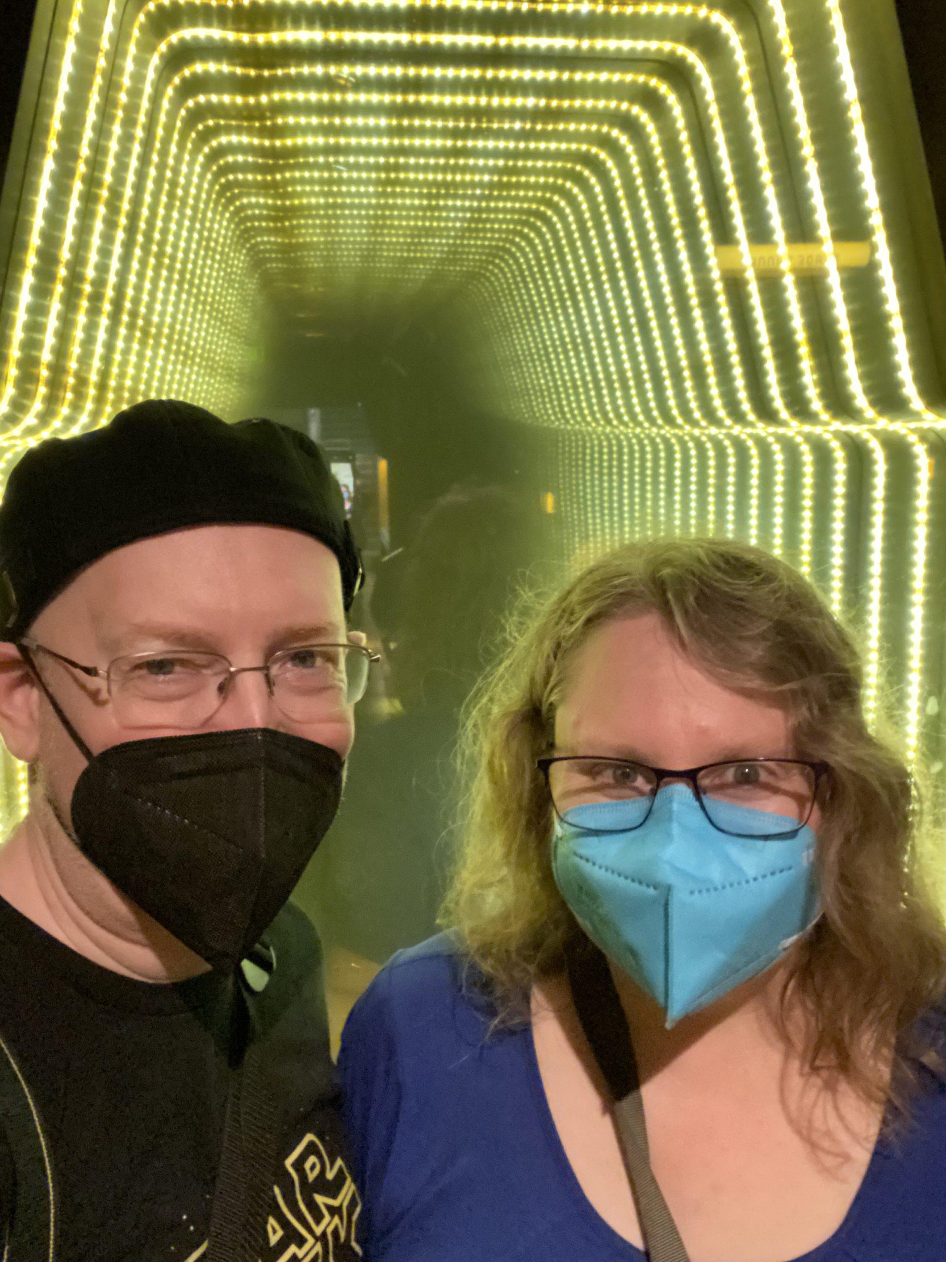 My wife and I in front of what looks like a science-fiction corridor, created with lights and mirrors.