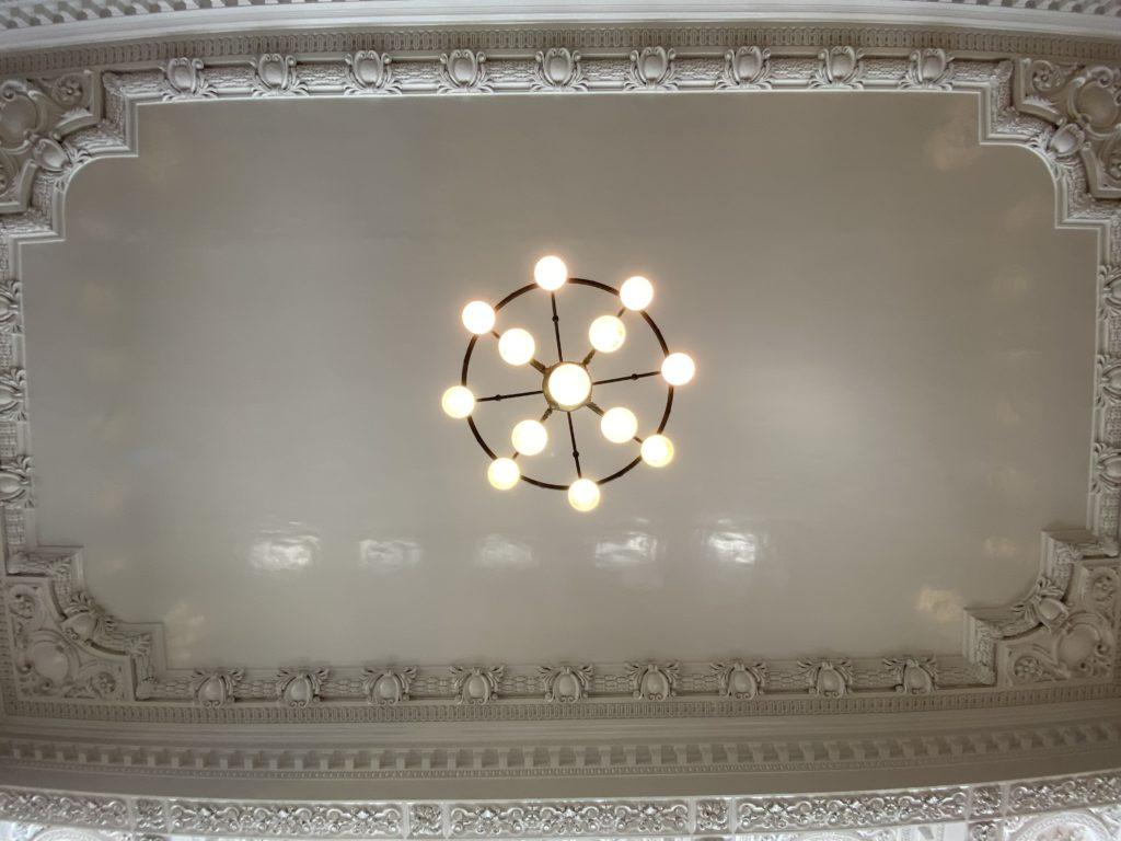 The ceiling of the train station shot from directly underneath a large chandelier.