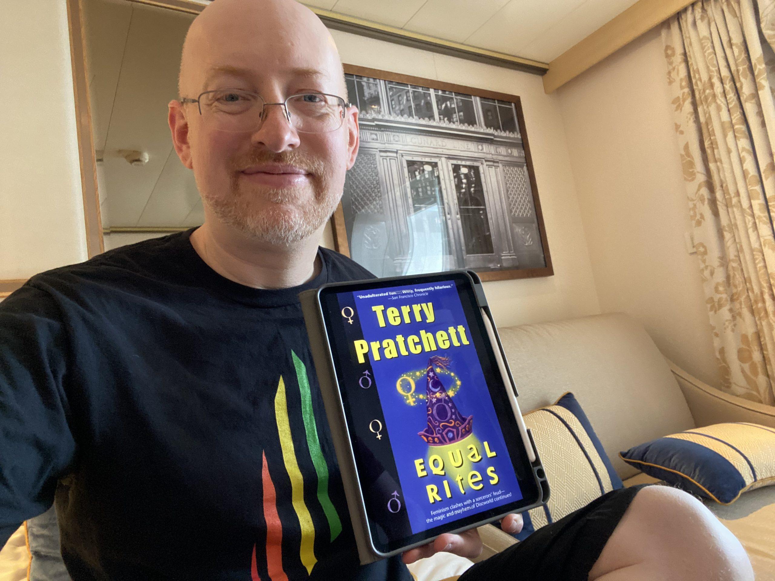 Me holding my iPad displaying the cover for Equal Rites on its screen