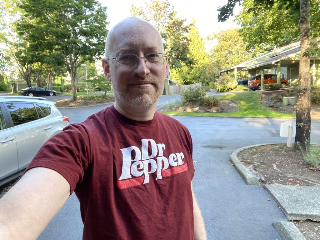 Me standing outside wearing a maroon-ish t-shirt with the Dr. Pepper logo.