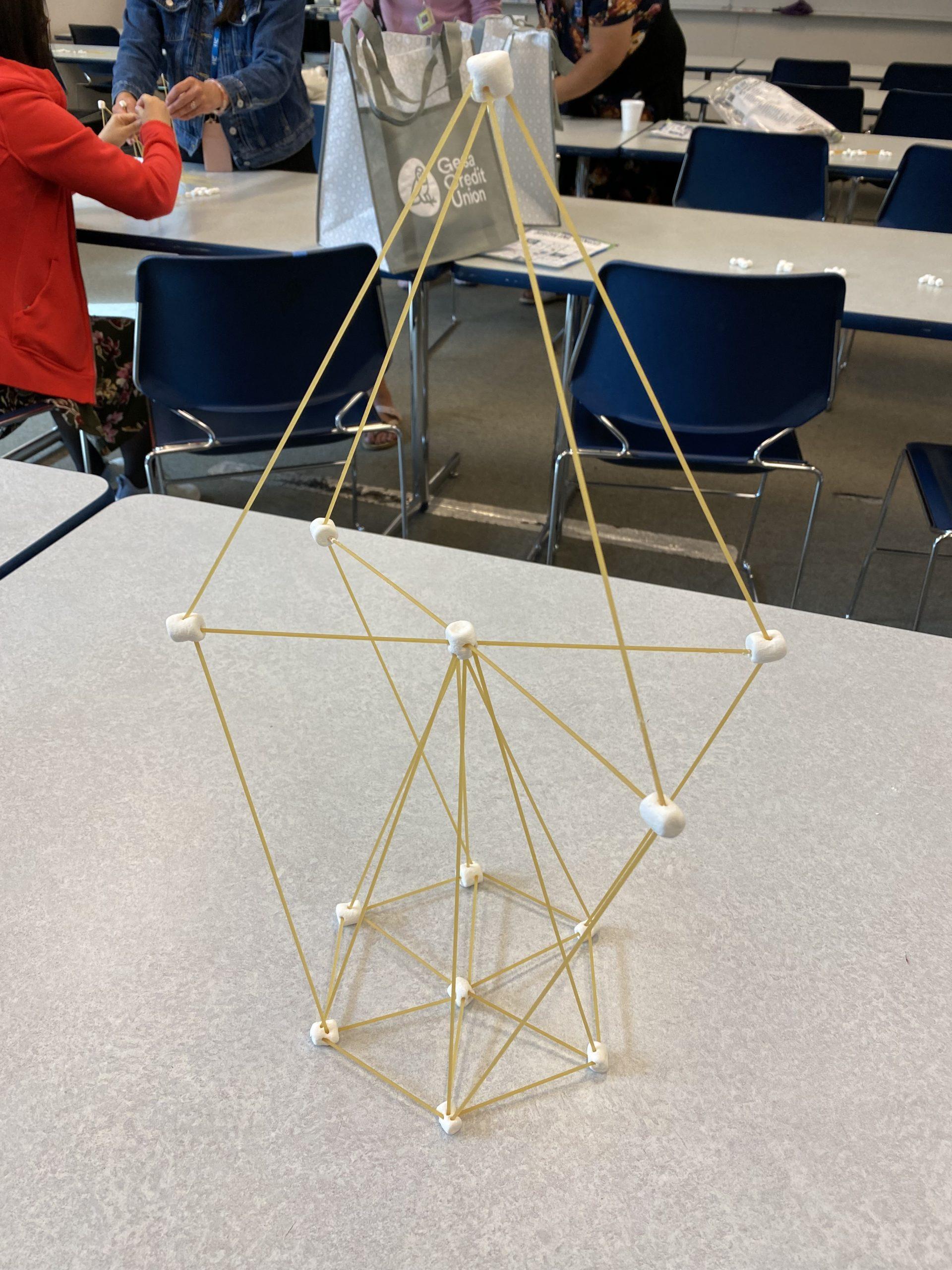 A vaugely pyramidal structure built of dry spaghetti and marshmallows, approximately 20 inches tall.