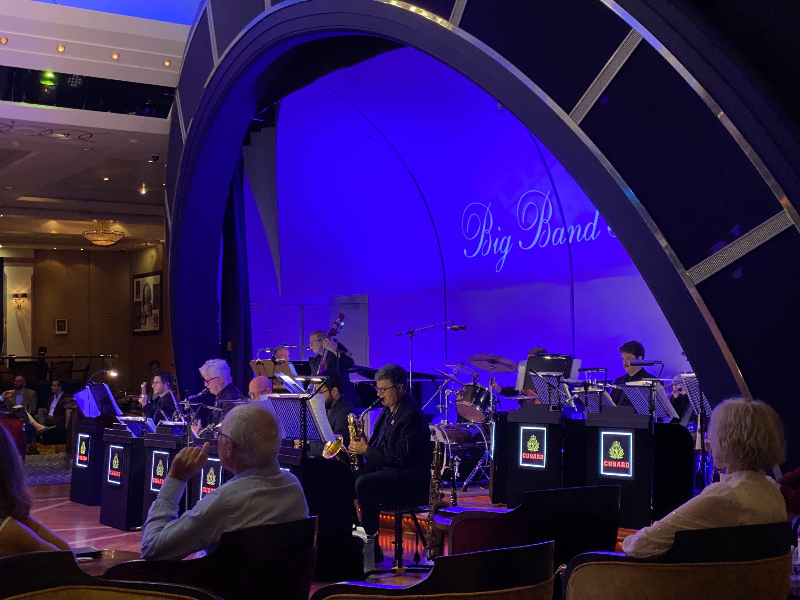 Musicians playing big band music from the stage at the front of the dancefloor of the ship's ballroom.