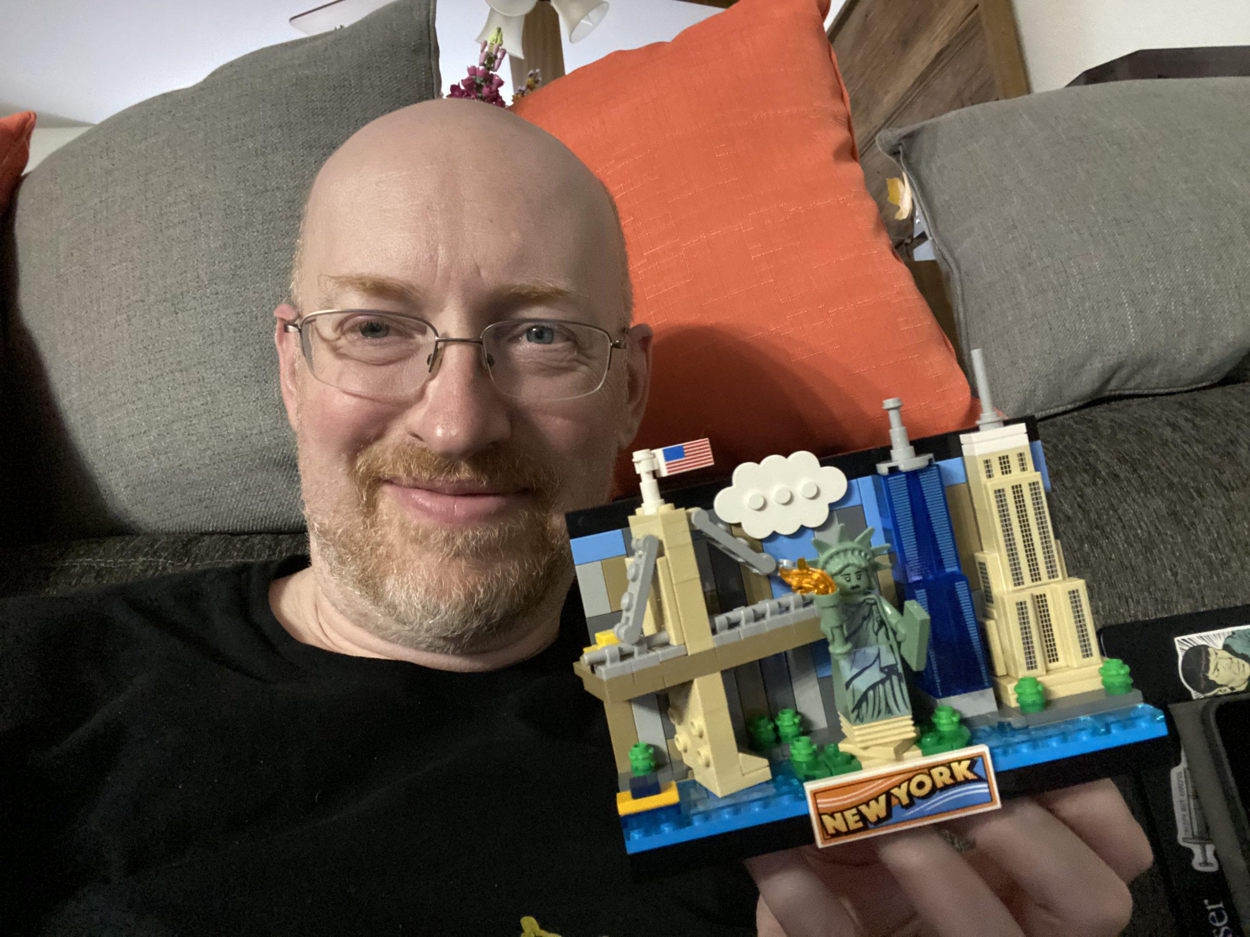 Me on the couch in our living room, holding a small Lego model of the New York City skyline.