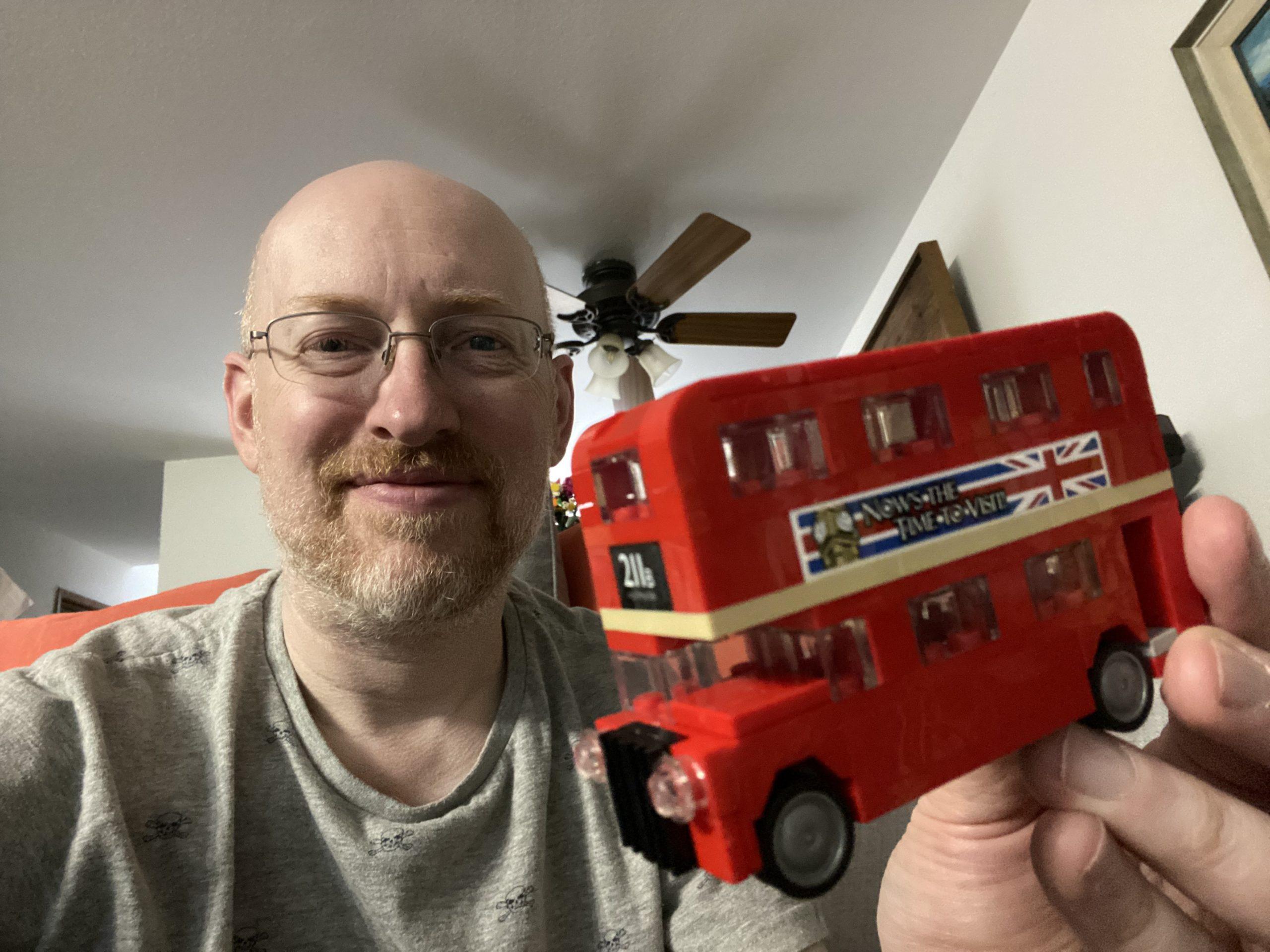 Me holding a small Lego classic red double-decker London bus.