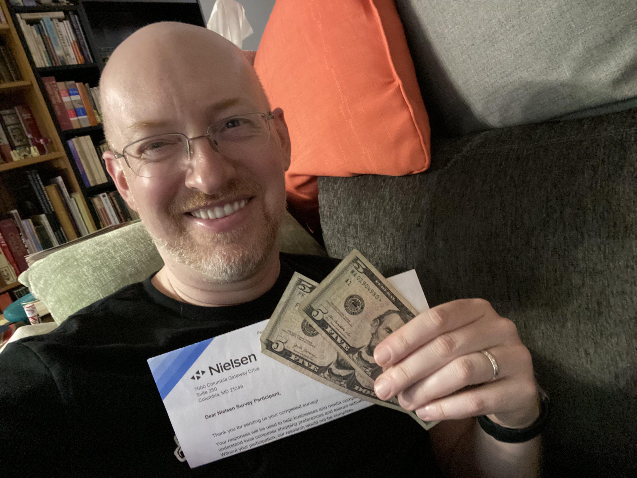 Me holding a thank you letter from the Nielsen company and two five dollar bills.