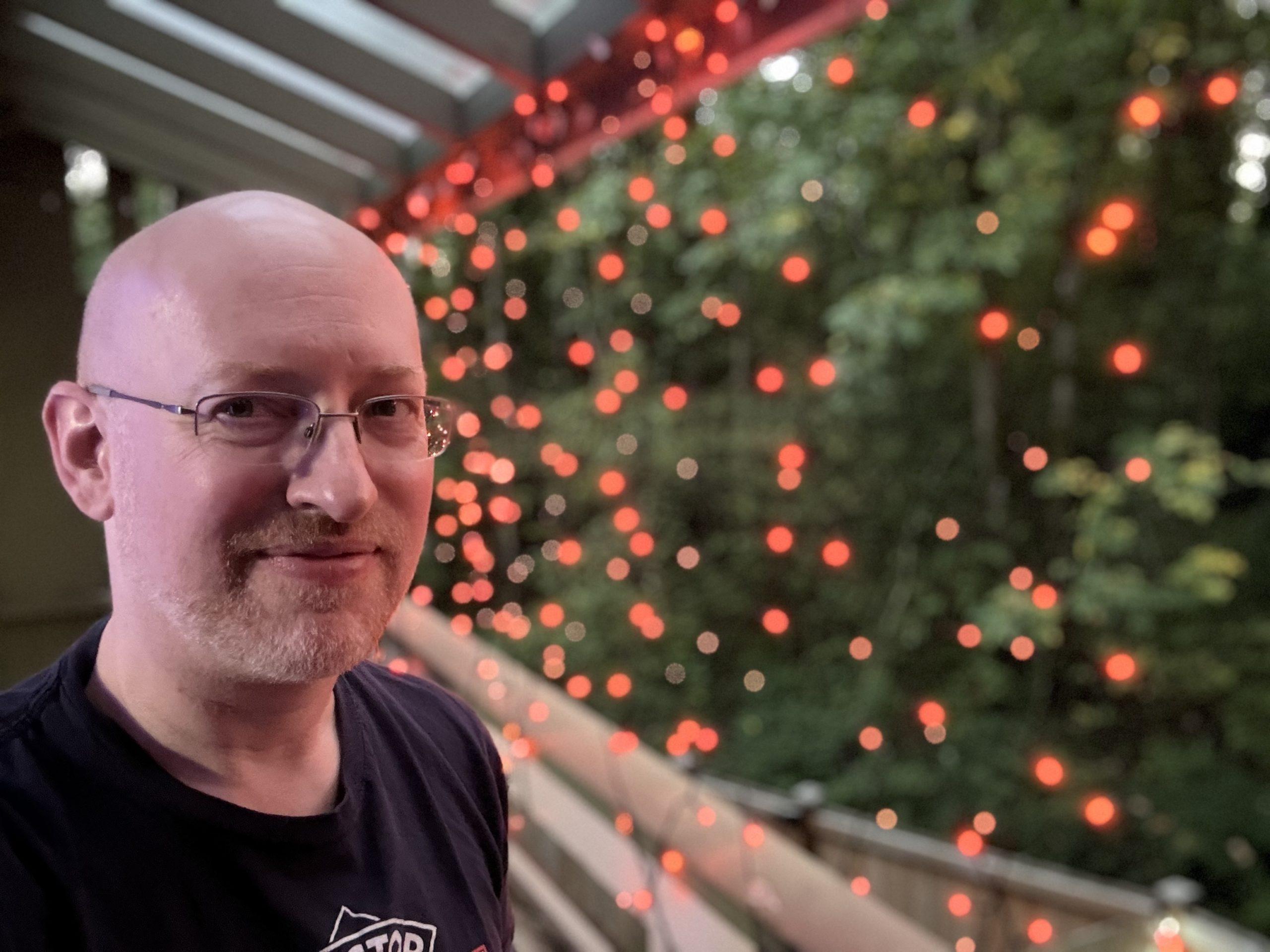 Me on our back porch, with lots of small orange lights strung across like a web.