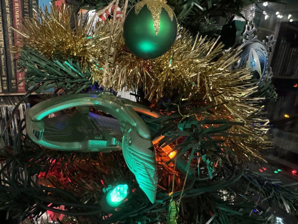 A close shot of a section of the tree, with two Star Trek themed ornaments showing; one a Romulan Warbird, the other the Starfleet logo.