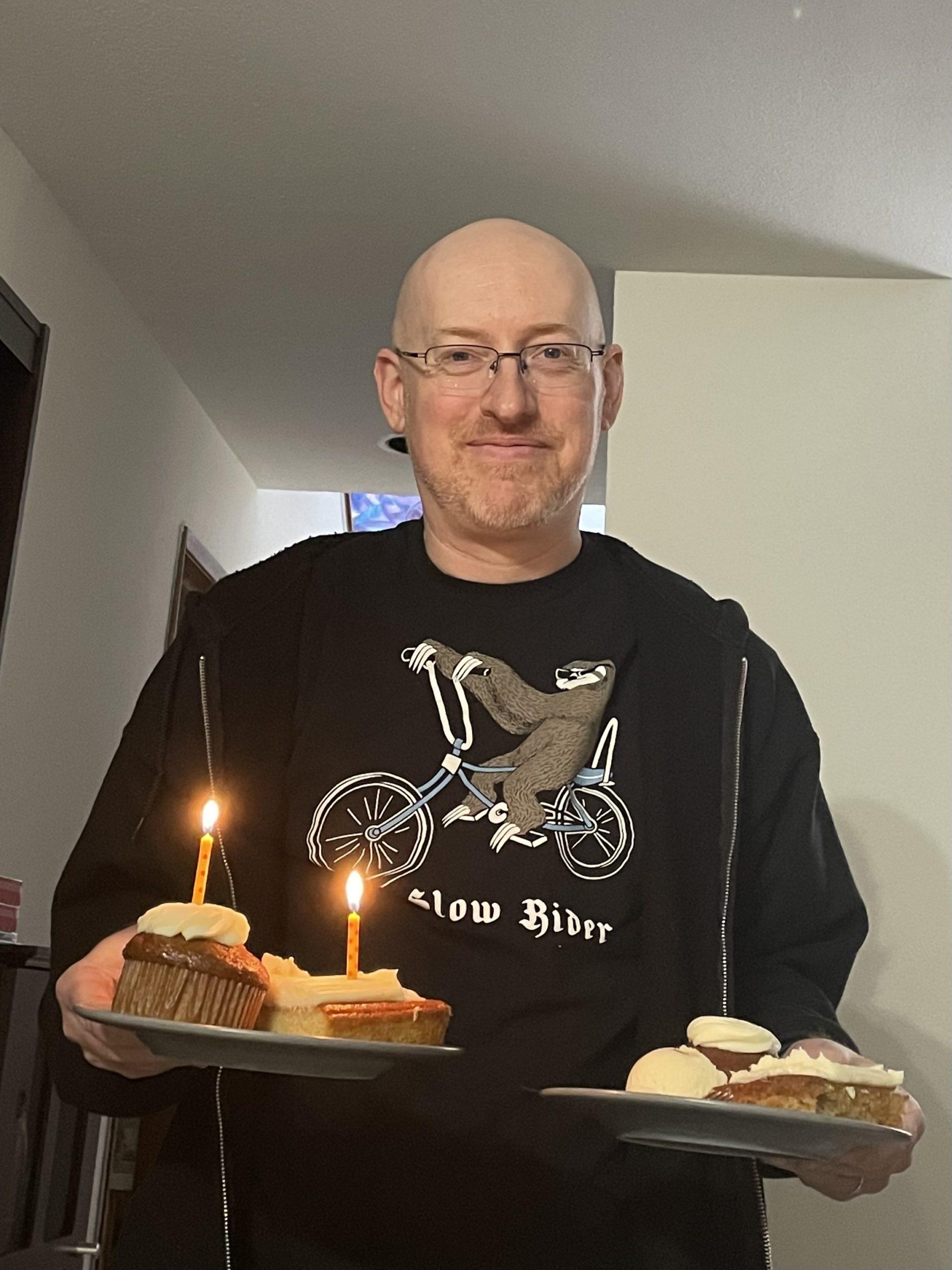 Me holding two plates of cake and ice cream, one with birthday candles in the cake.