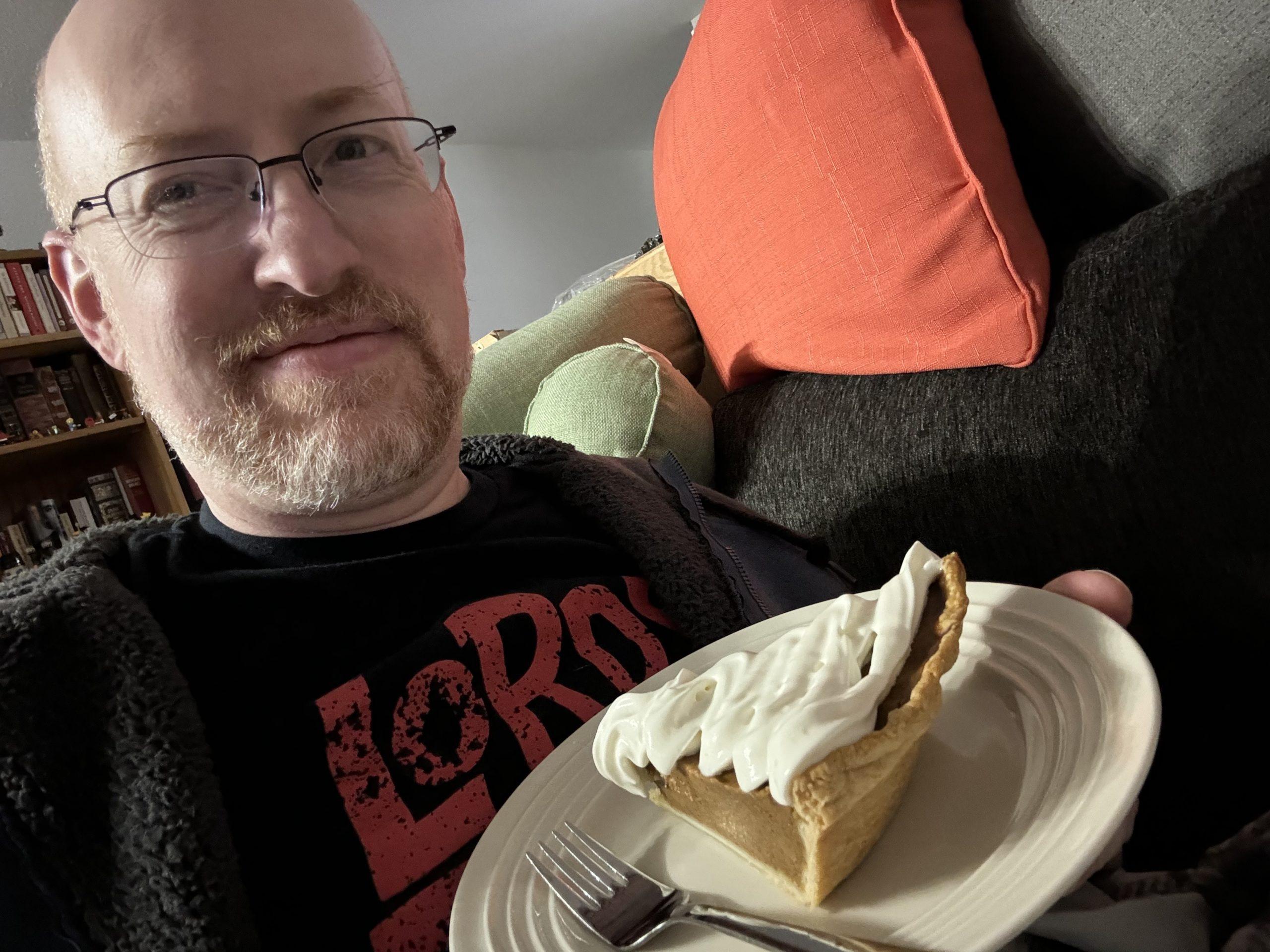 Me holding a plate with a piece of pumpkin pie.