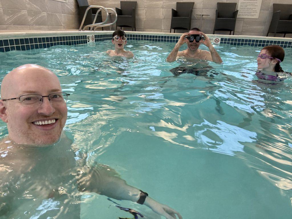 Me in a swimming pool with my niblings and their father.