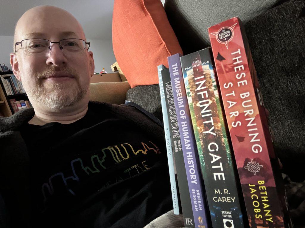 Me holding a stack of books consisting of five out of this year’s six Philip K. Dick Award nominees.