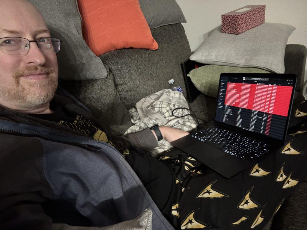 Me on the couch in my Star Trek pajamas, with my MacBook Air open on my lap and the Music app running full screen and displaying a long list of tracks.