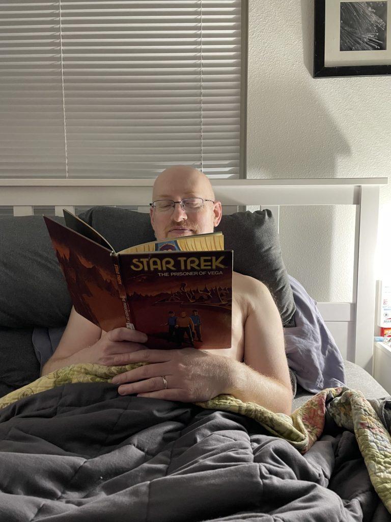 Me tucked in bed, reading an old Star Trek children’s book.