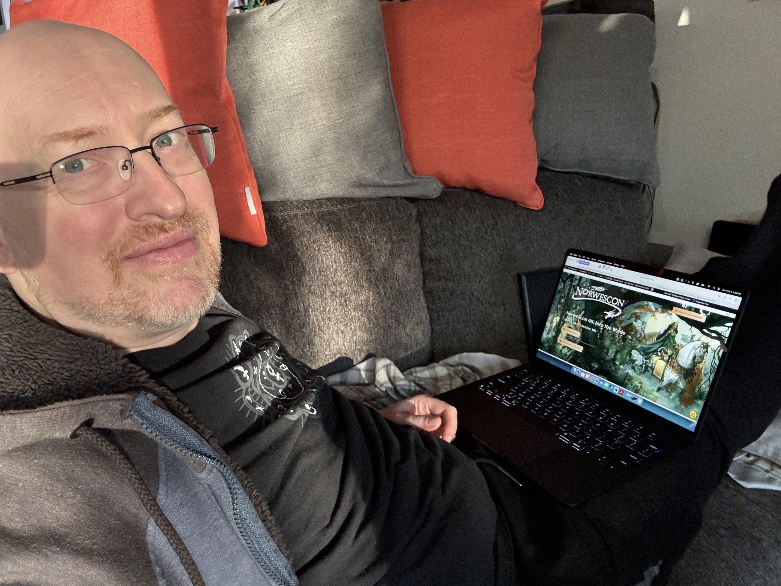 Me in a sunbeam on our couch, with the Norwescon website visible on the laptop open on my lap.