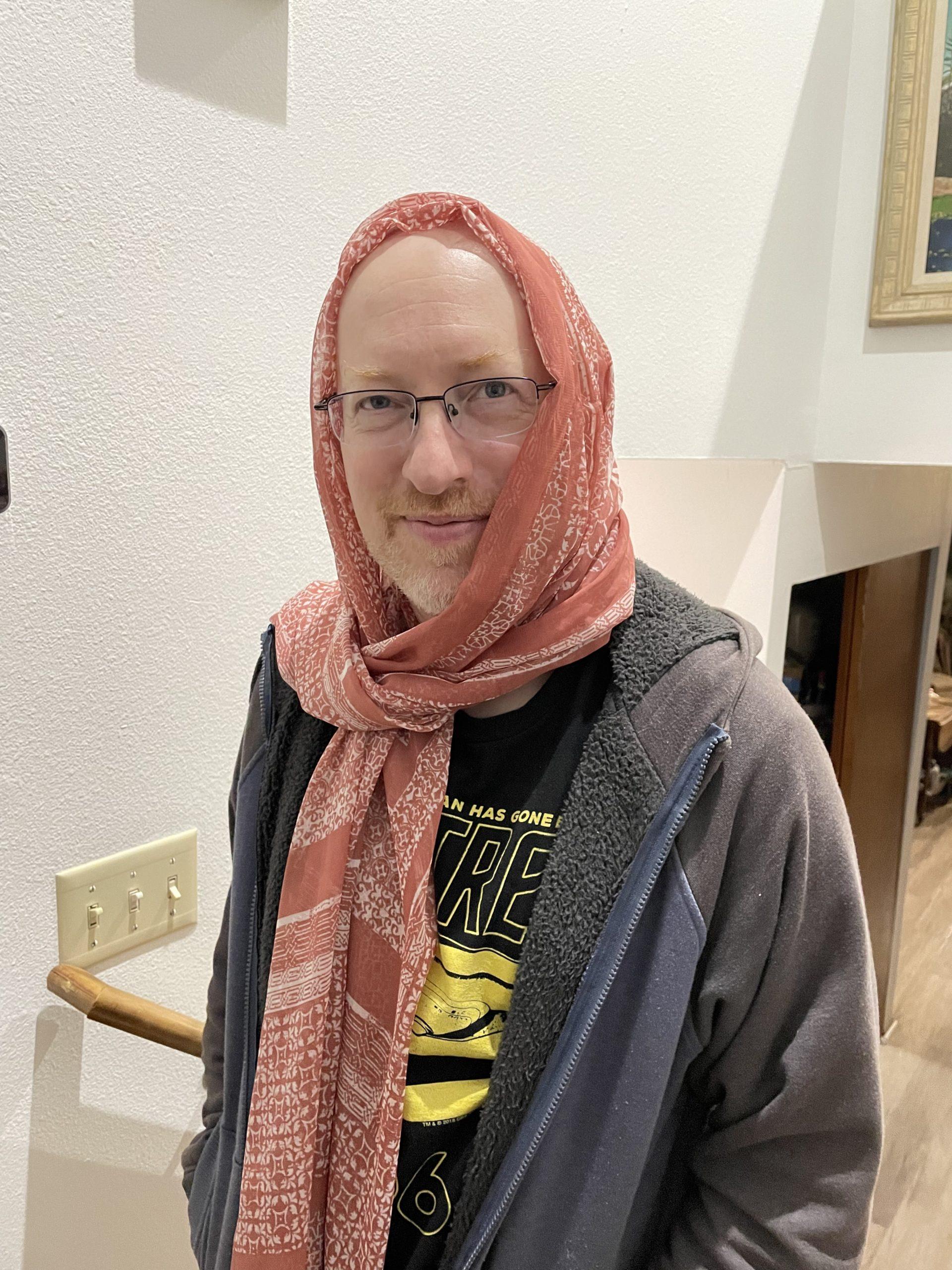 Me wearing a t-shirt and hoodie, with a salmon-colored scarf wrapped around my head.
