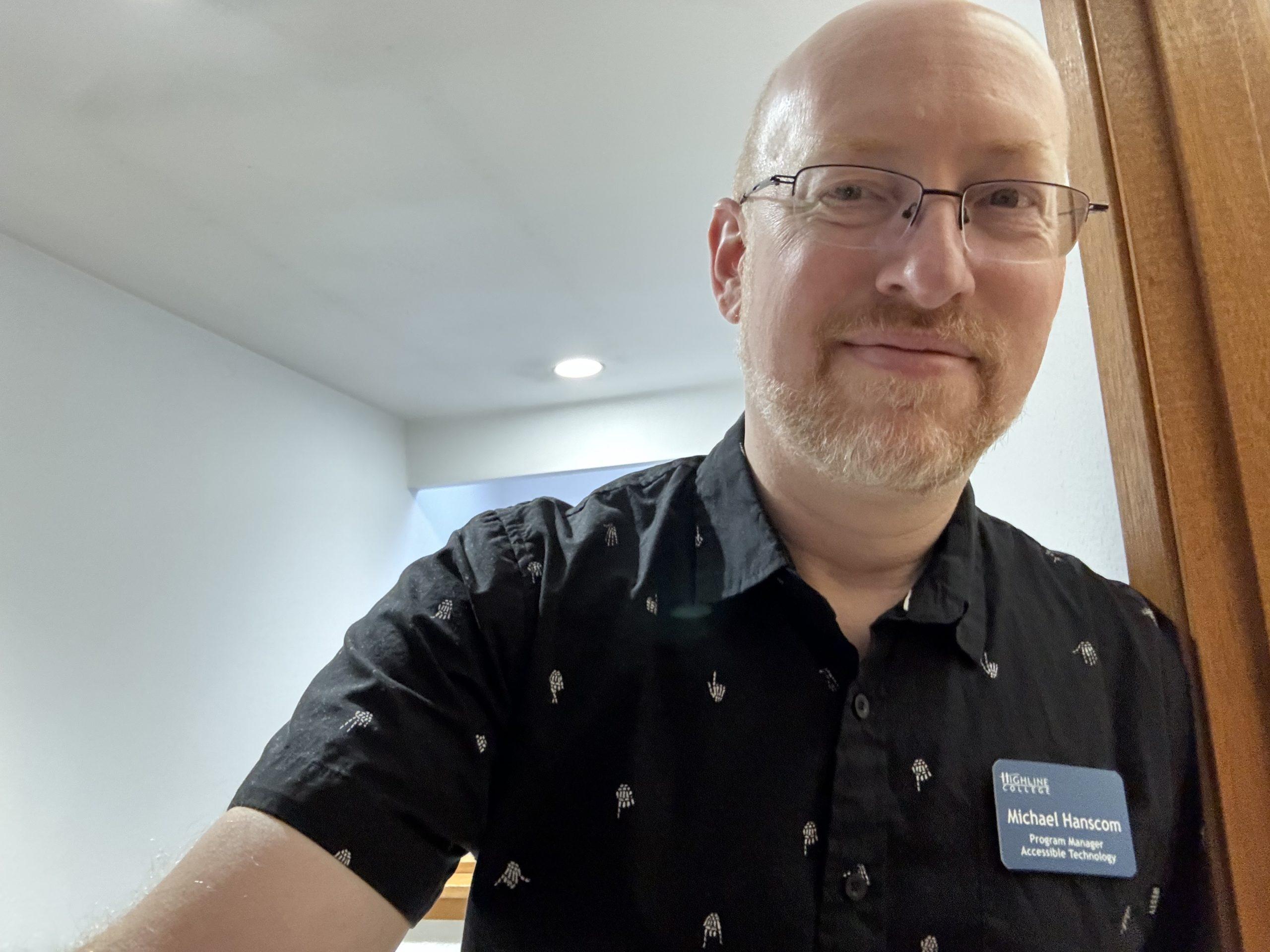 Me leaning against a doorway, wearing a black shirt with tiny white skeletal hands.