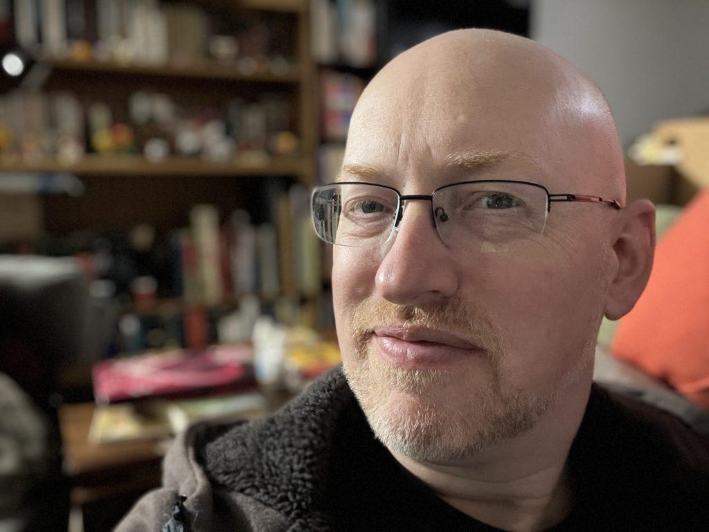 A portrait style selfie, with my head freshly shaved and face fuzz trimmed back to being very short.