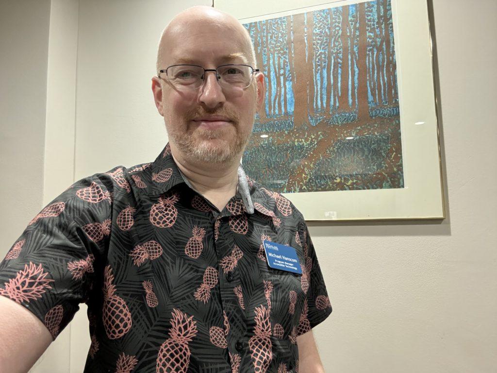 Me wearing a black short-sleeve button-up shirt with a pattern of pineapples. 