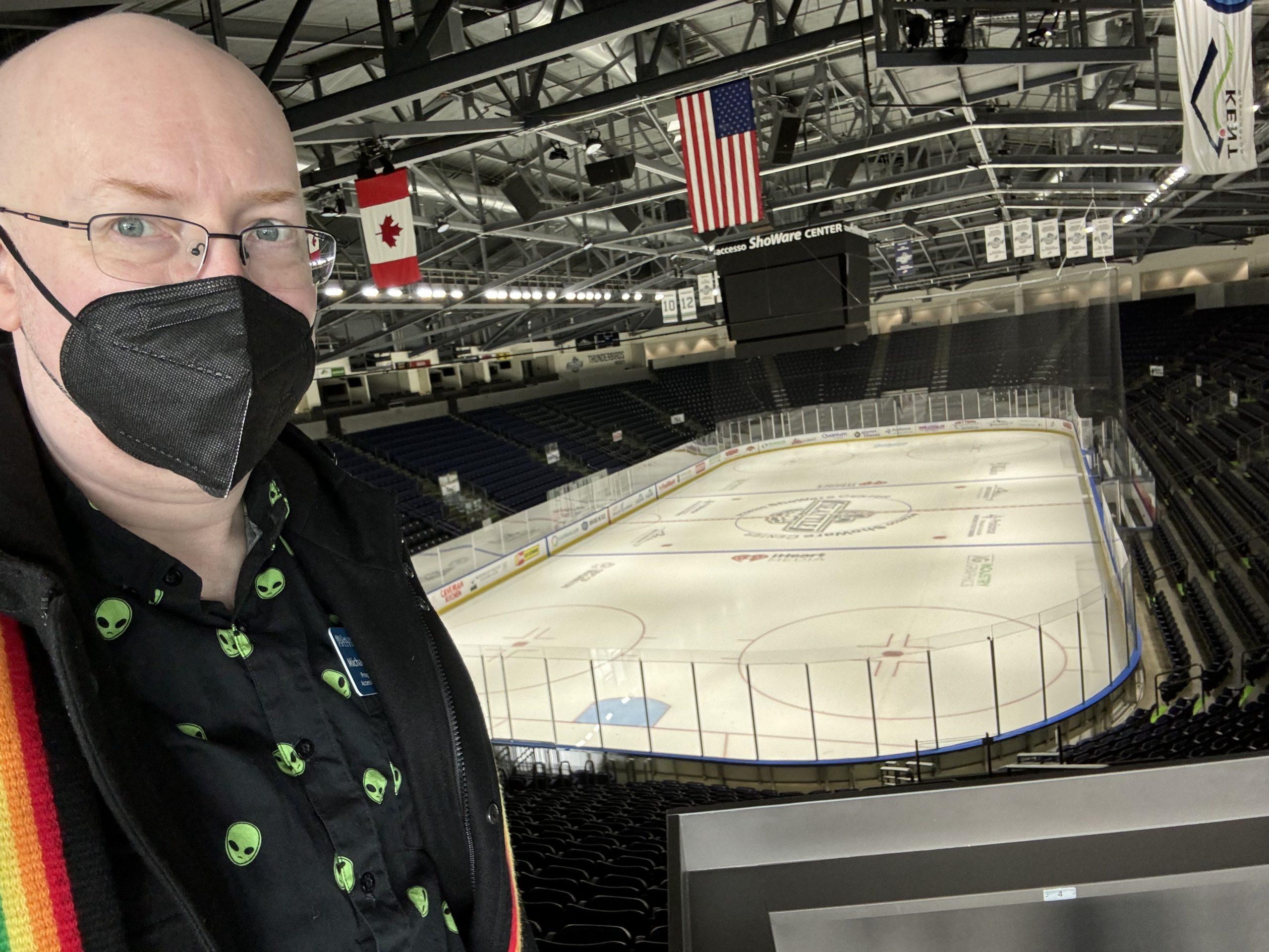 Me, wearing a black face mask, with a hocky arena visible behind me.