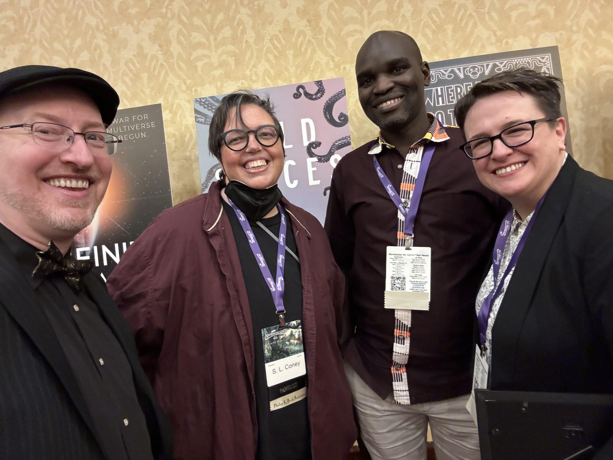 A selfie with me, S.L. Coney (a white woman with short cut brown hair and glasses wearing a black shirt under a purple top), Dilman Dila (a tall Black man wearing a purple shirt with a colorful patterned collar), and Bethany Jacobs (a white woman with short brown hair and glasses wearing a black suit jacket over a light top).