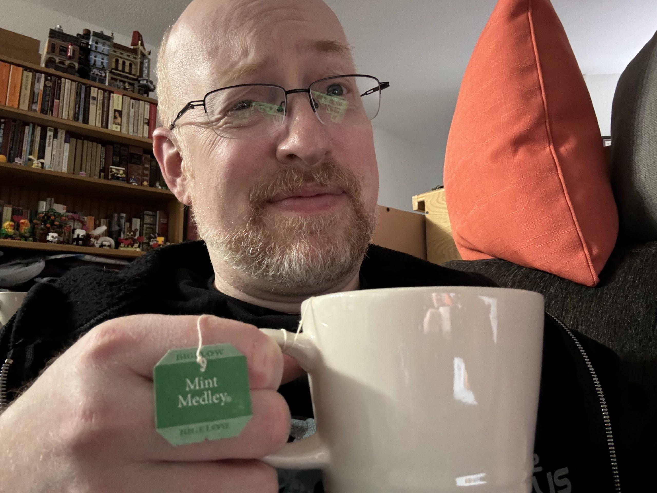 Me with a sad expression, holding a mug of Mint Medley tea.