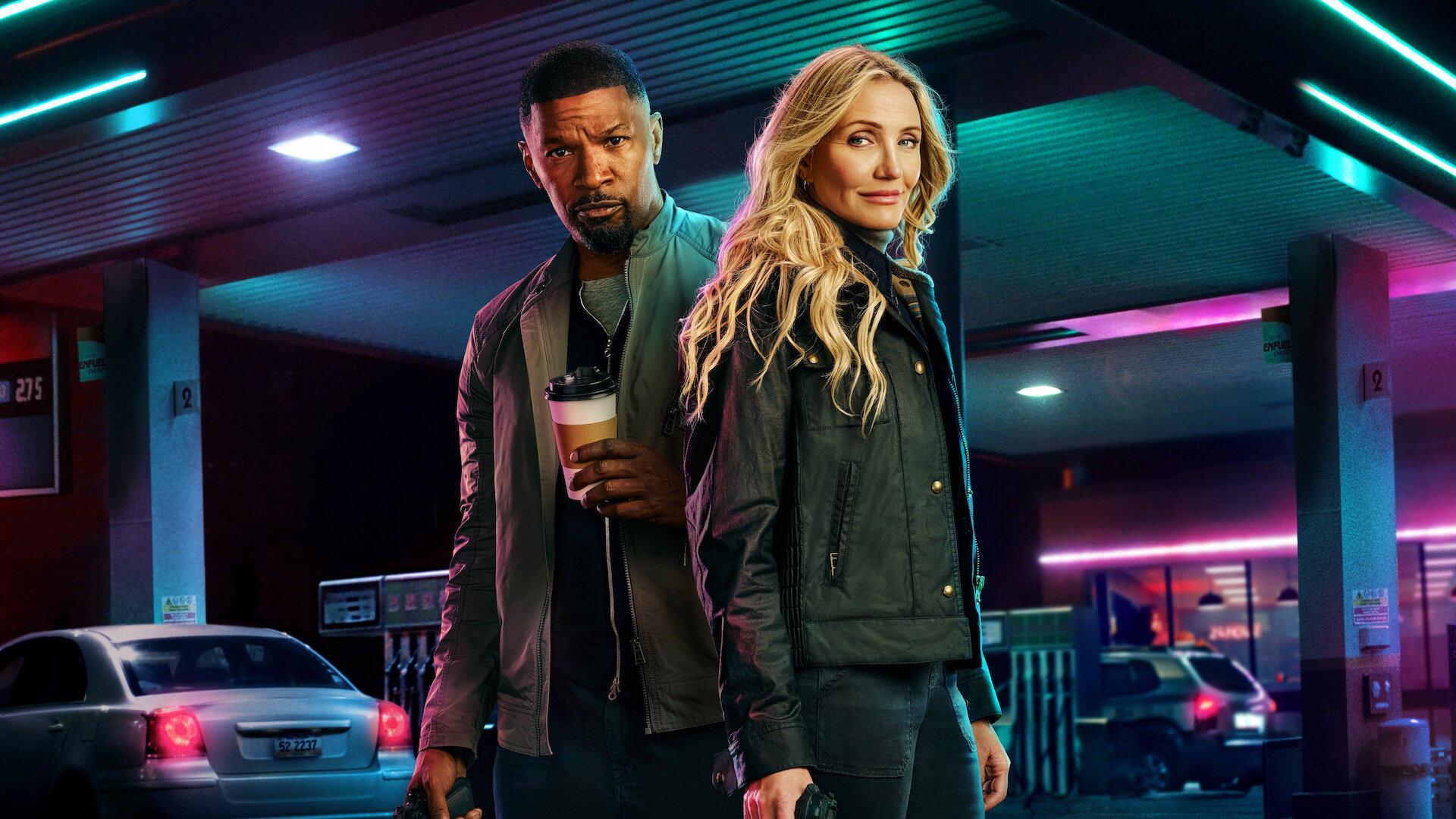 Jamie Foxx and Cameron Diaz pose in front of a neon-lit gas station.