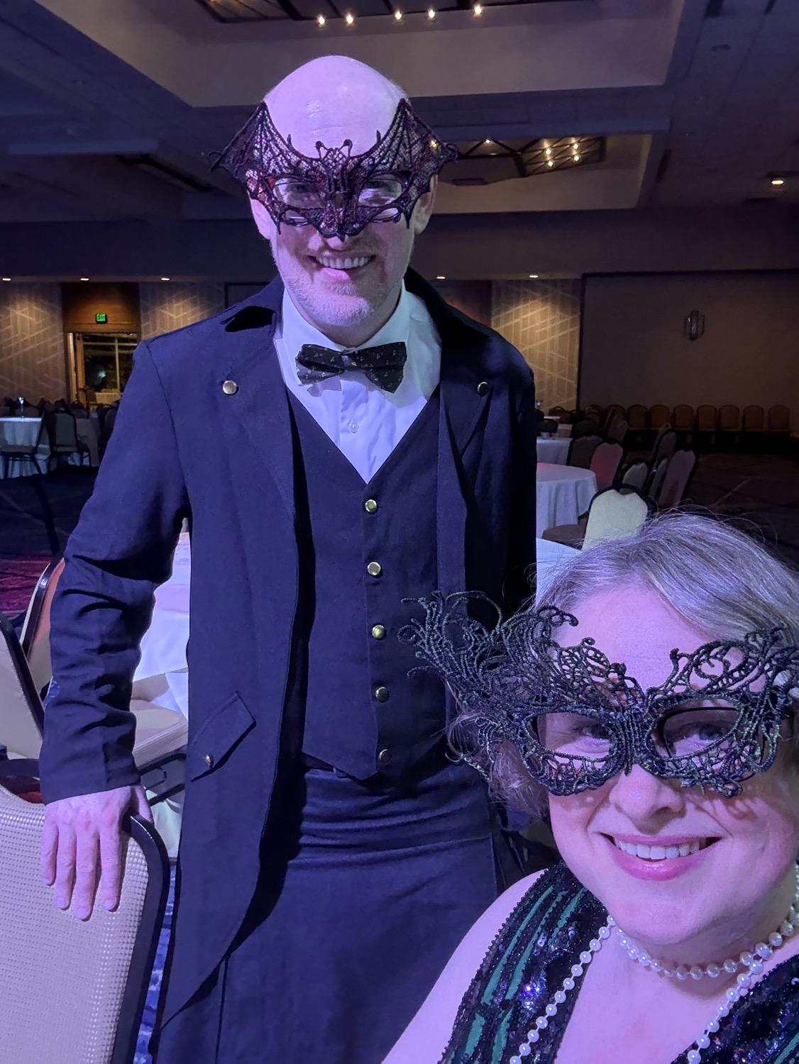IMG_0902.jpeg My wife and I at the dance, me in a long black frock coat over white shirt and bow tie, her in a green flapper dress, both of us wearing lacy masks.