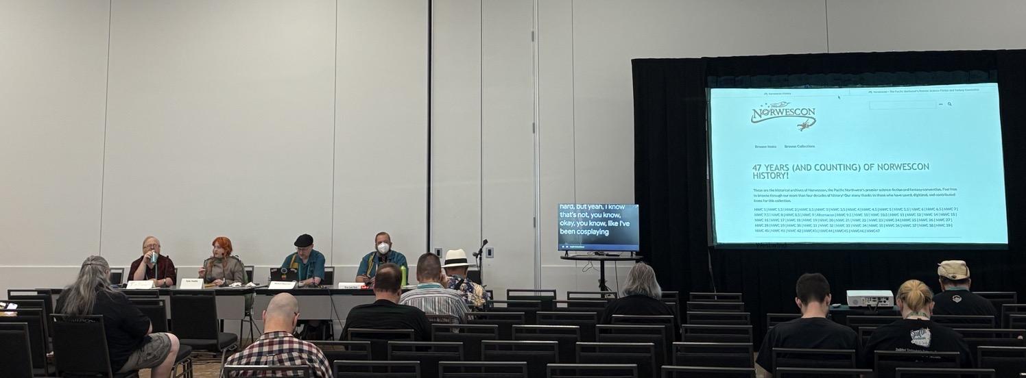 IMG_1128.jpeg Wide shot of the panel, with the panelists on the left and a large video screen showing the Norwescon history website on the right.