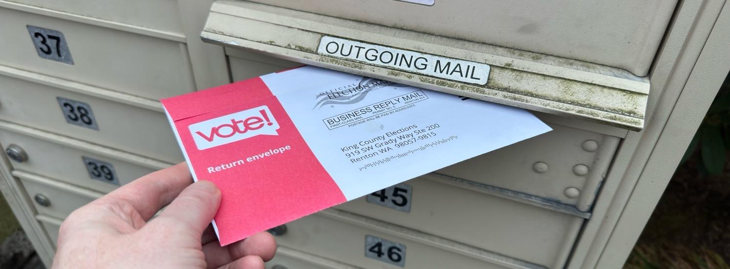 My hand putting a ballot into our mailbox.
