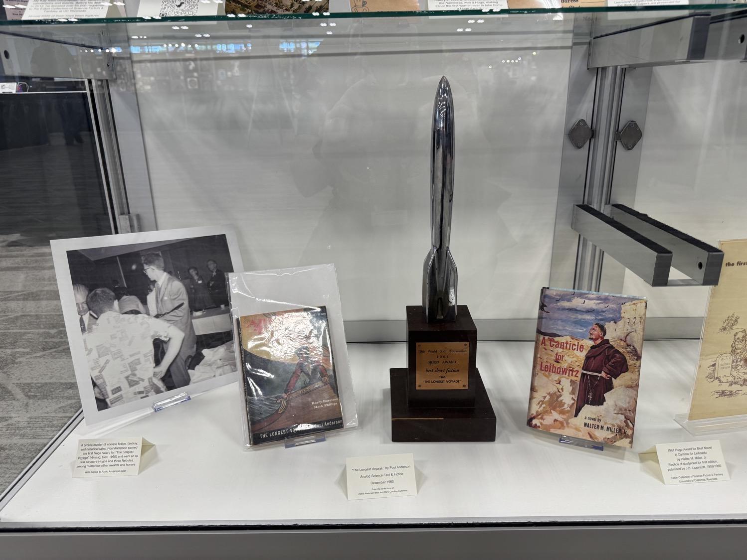 IMG_4682.jpeg A display case with a photo of Poul Anderson receving his first Hugo for 'The Longest Voyage', the issue of Amazing Stories with that story, his Hugo award trophy, and a copy of A Canticle for Liebowitz, the Best Novle Hugo winner for that year.