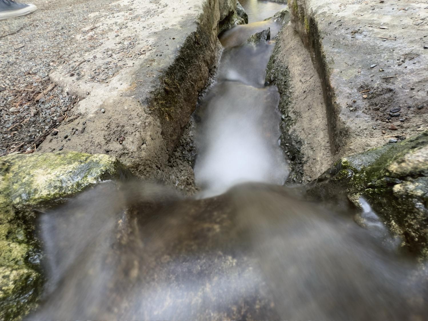 A small stream runs down a cleft in rocks; the water is motion blurred and smooth.
