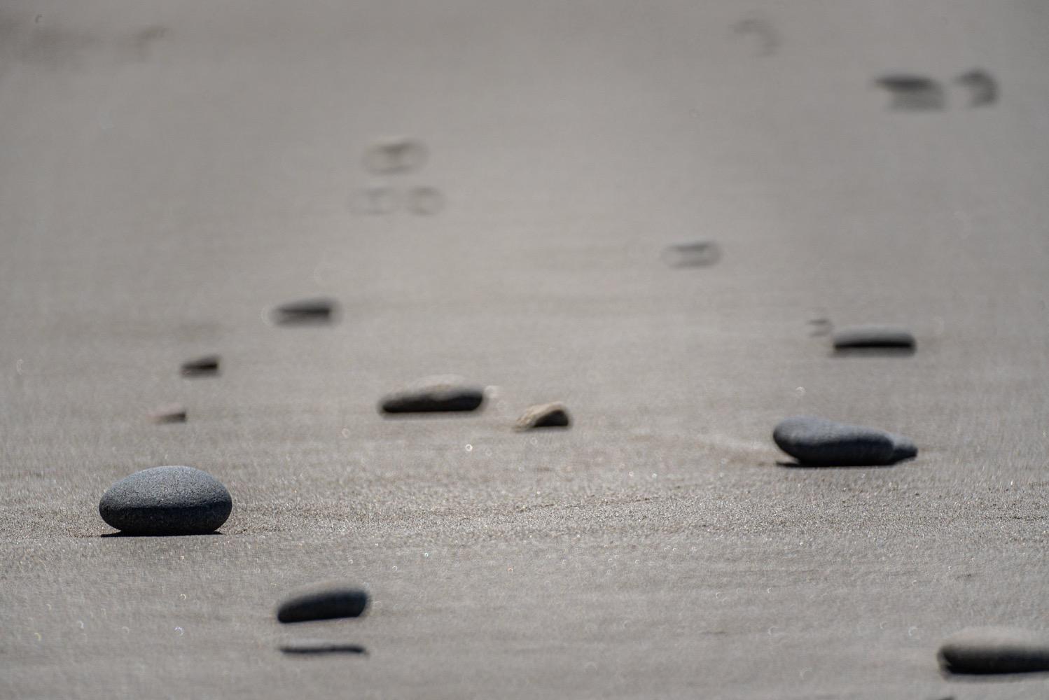 Flat stones on a sandy beach, in a nearly monochromatic image.