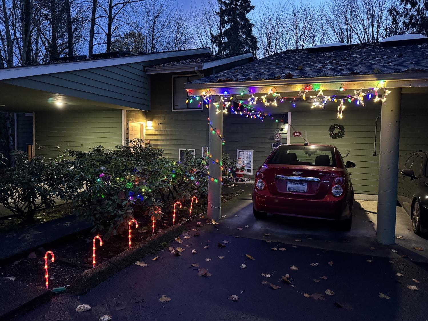 The carport of a fourplex condo, decorated with colorful holiday lights, stars, and candy canes.