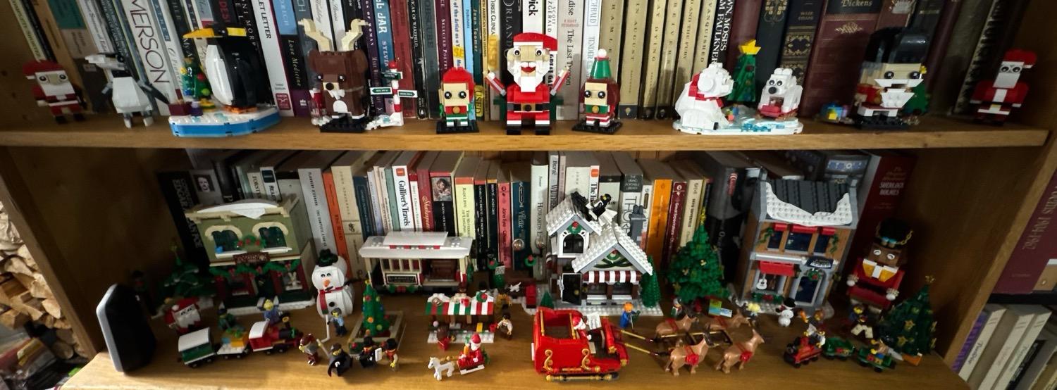 Two bookcase shelves decorated with various winter and Christmas themed LEGO sets.
