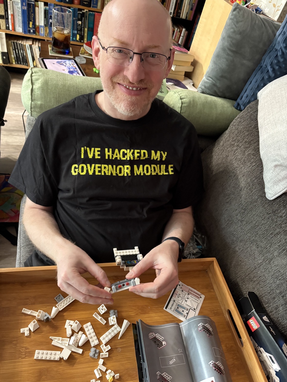 Me sitting on a couch, wearing a shirt that says, 'I've hacked by governor module', assembling Legos.