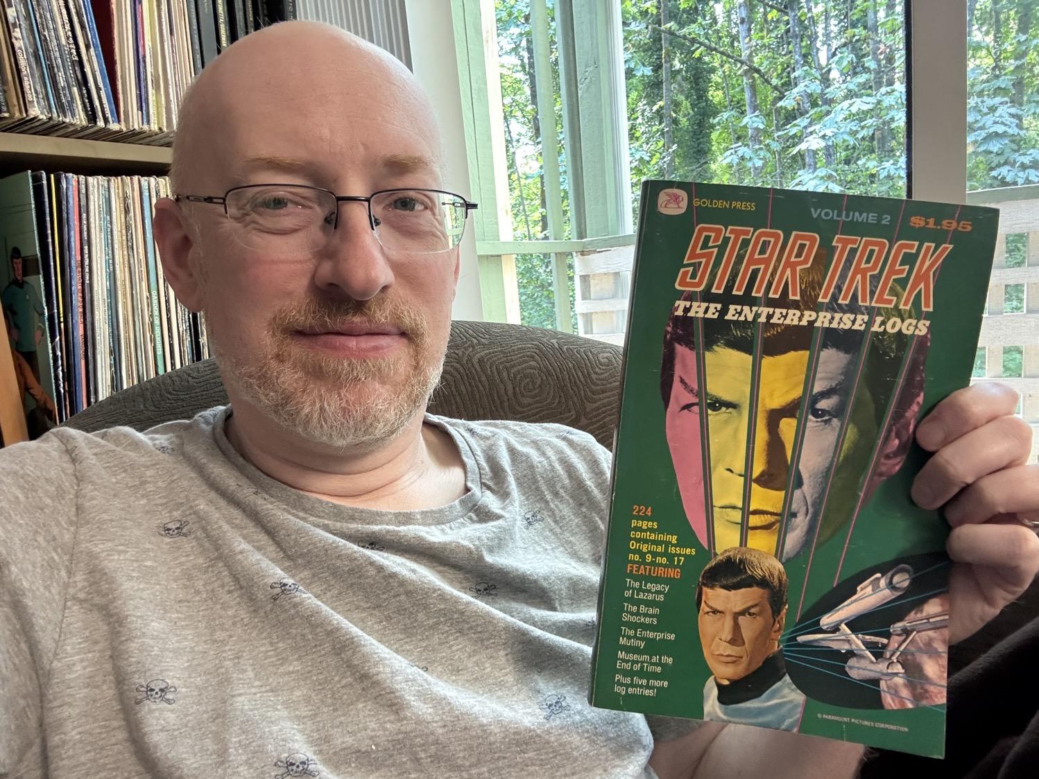 Me holding The Enterprise Logs Volume 2