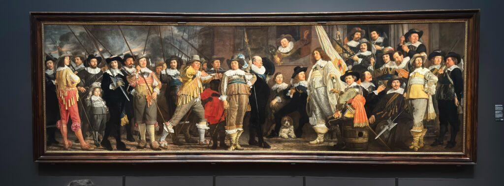 Very wide painting of a group of men in fancy 1600’s military dress.
