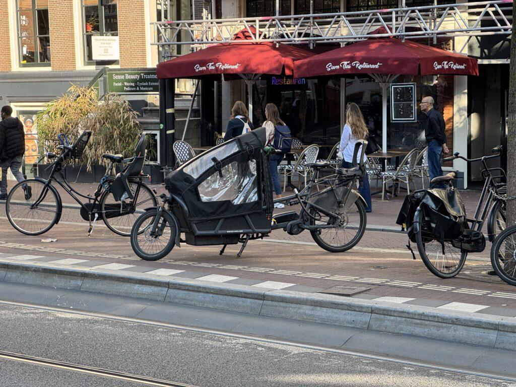 A bicycle with a smaller front wheel and an extended front section covered to form a small enclosure for a child to ride in.